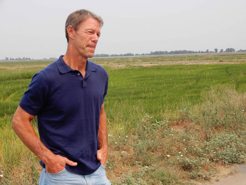 Les  Canter, general partner with River Garden Farms, with a rice field in the background.  River Garden has experimented with winter flooding of rice fields to produce food for fish. 